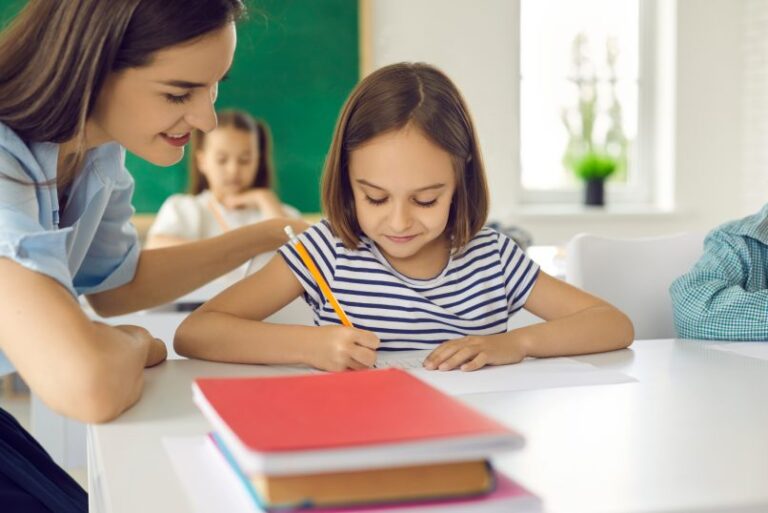 Profesora con niña escribiendo en una clase