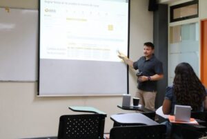 Profesor en sula exponiendo indicando la pantall